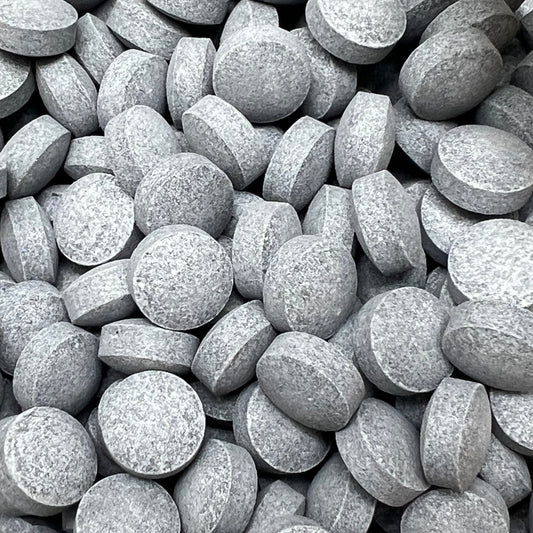 close up showing toothpaste tablets, dark gray speckled disk shape