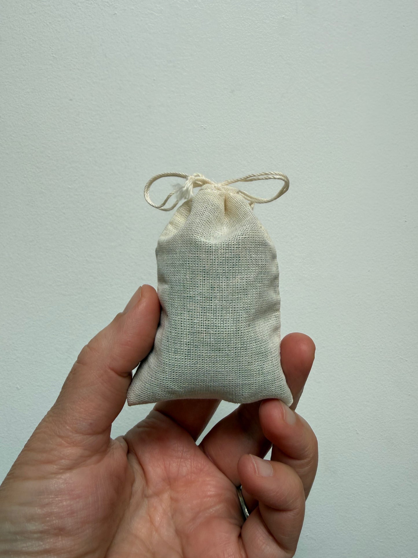 Hand holding a cotton muslin bag filled with lavender flowers.