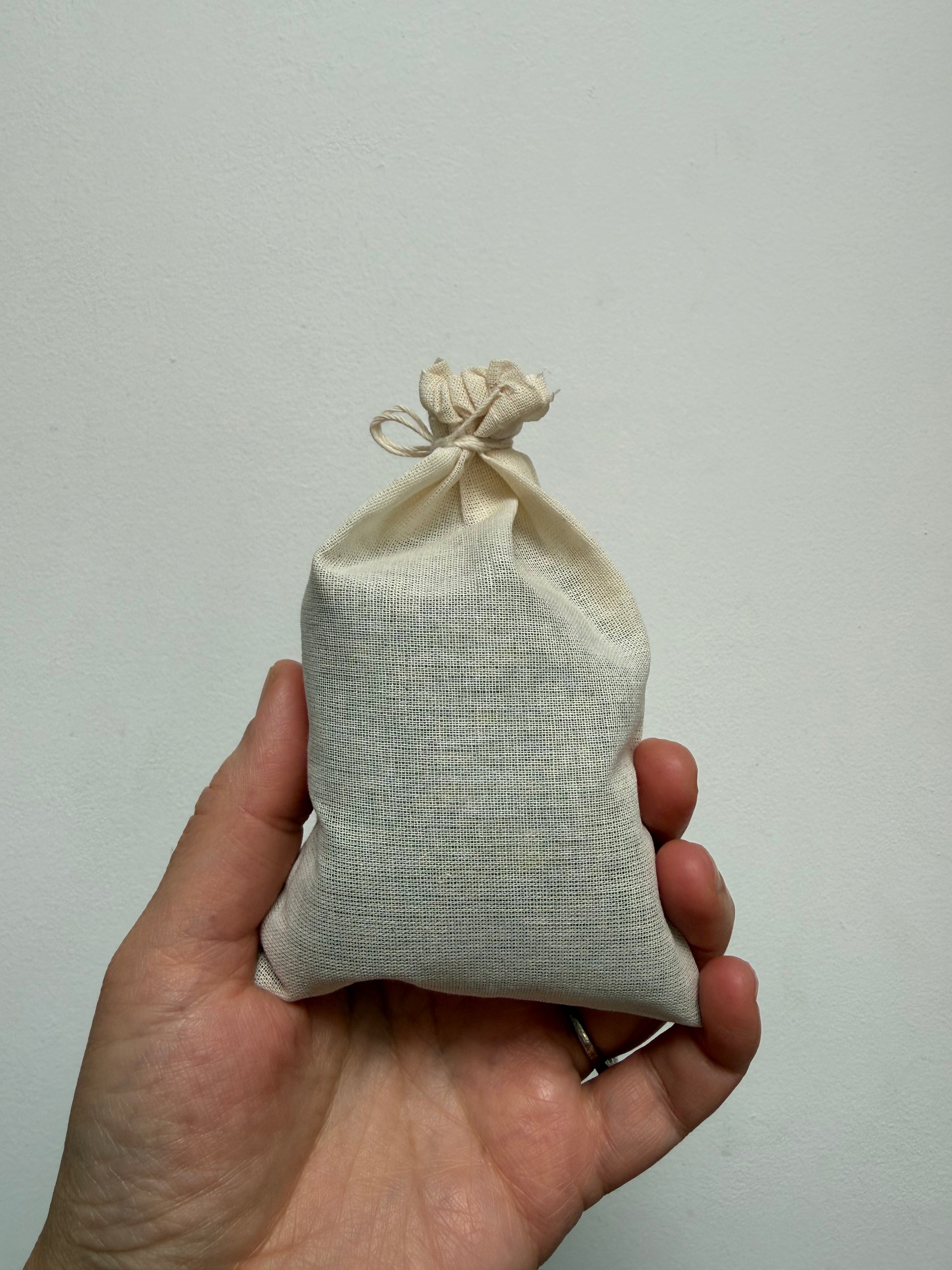 Hand holding a cotton muslin bag filled with lavender flowers.