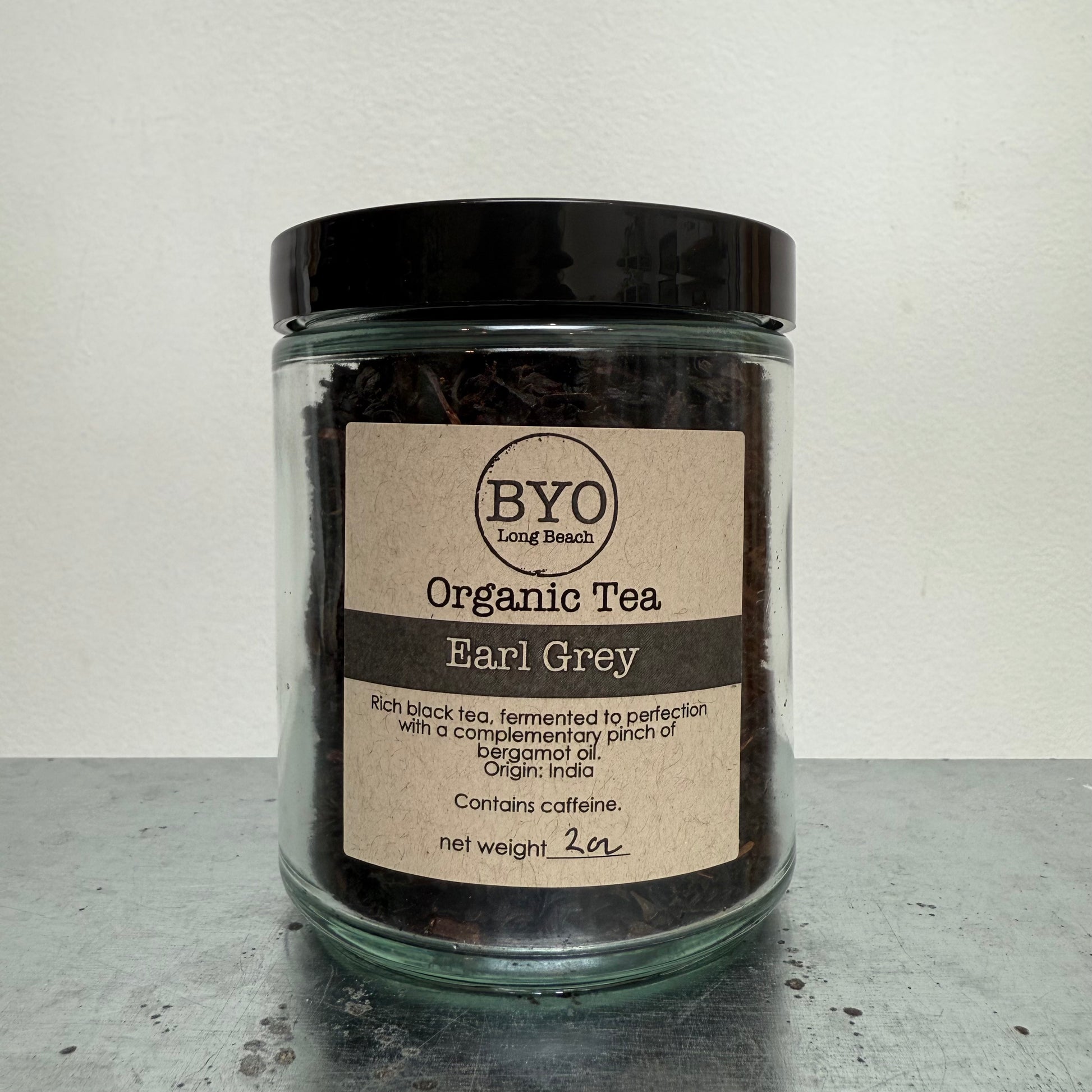 Jar of organic tea labeled 'BYO Organic Tea' on a gray surface with a white background
