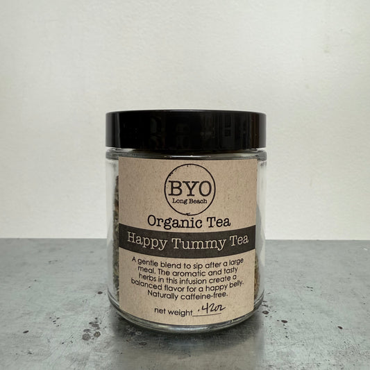 Jar of Organic Tea labeled 'Happy Tummy Tea' by BYO on a gray surface with a white background