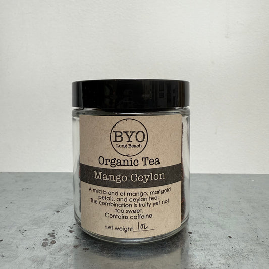 Glass jar of Organic Tea Mango Ceylon with a black lid on a gray surface.