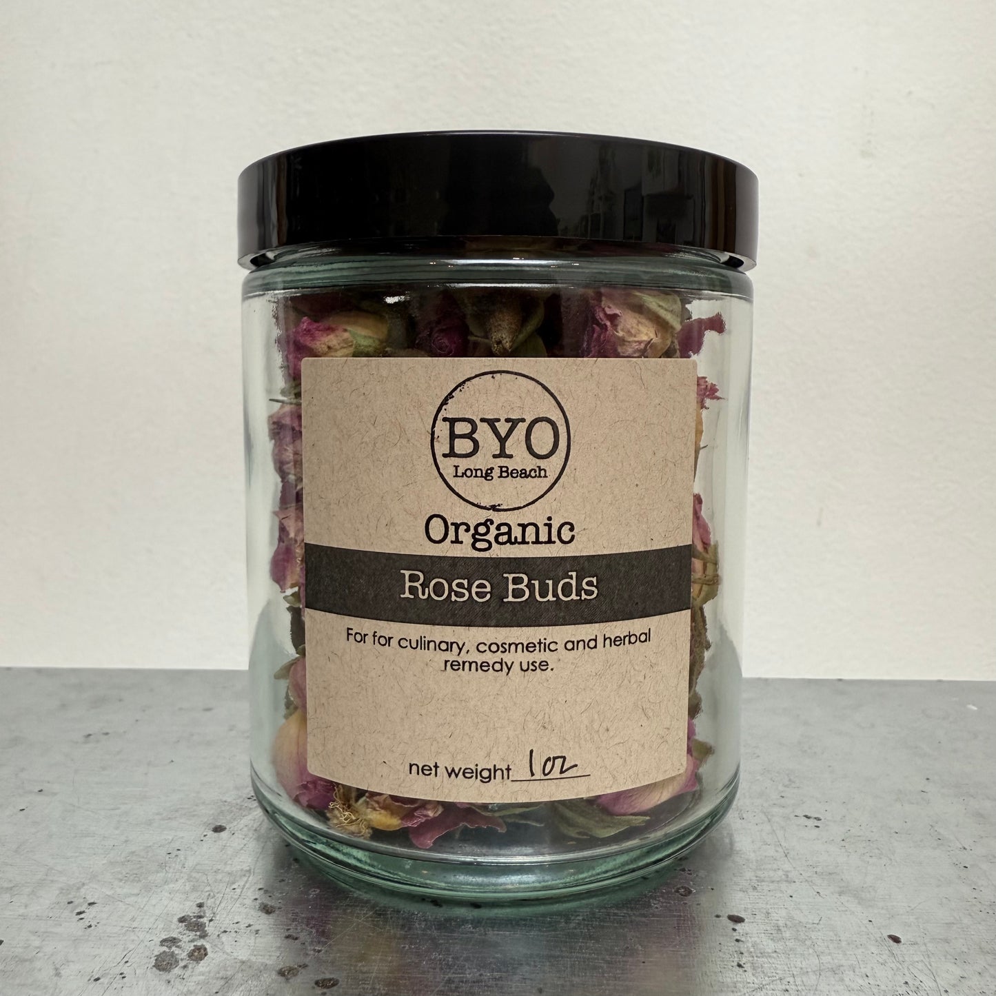 Jar of organic rose buds with a 'BYO' label on a neutral background