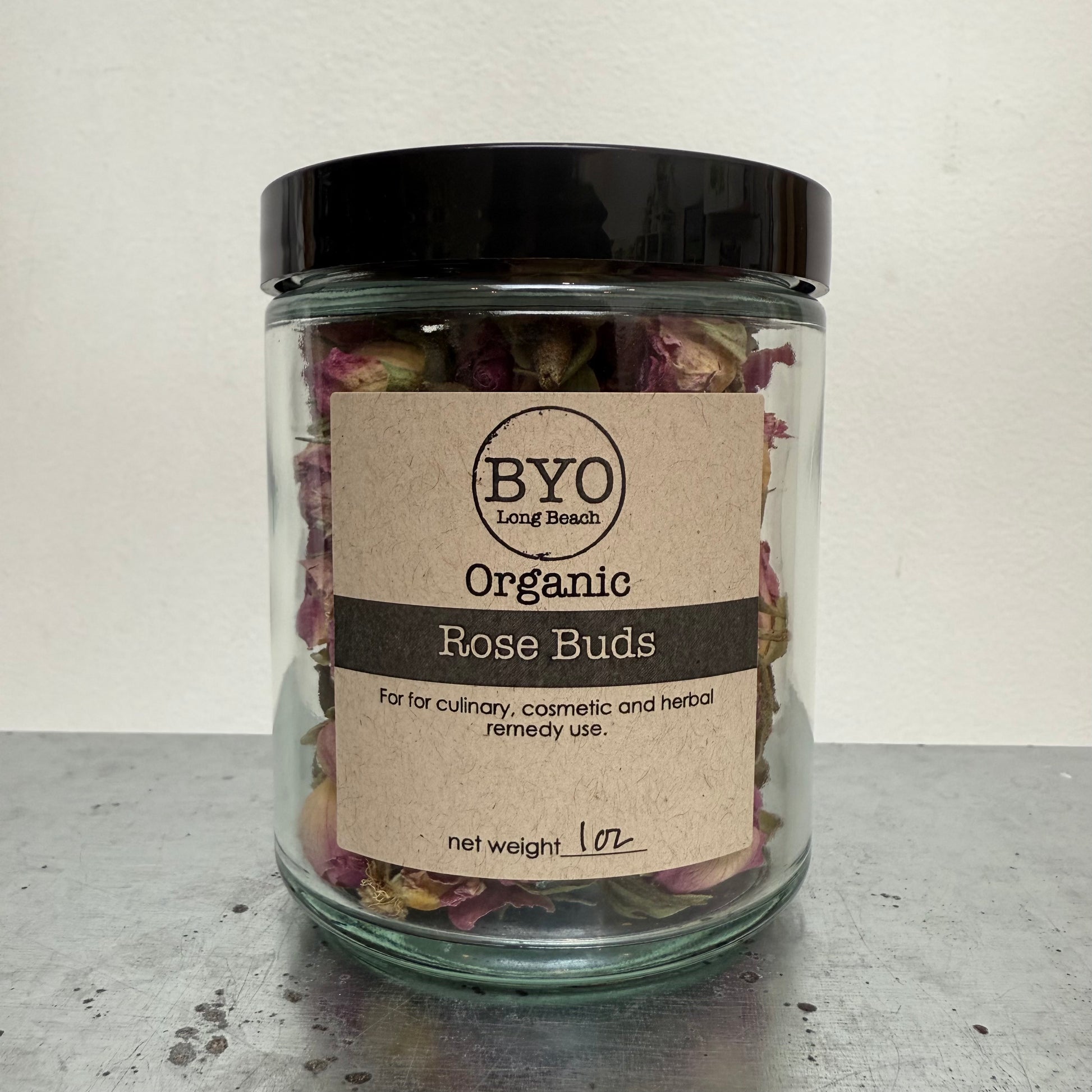 Jar of organic rose buds with a 'BYO' label on a neutral background