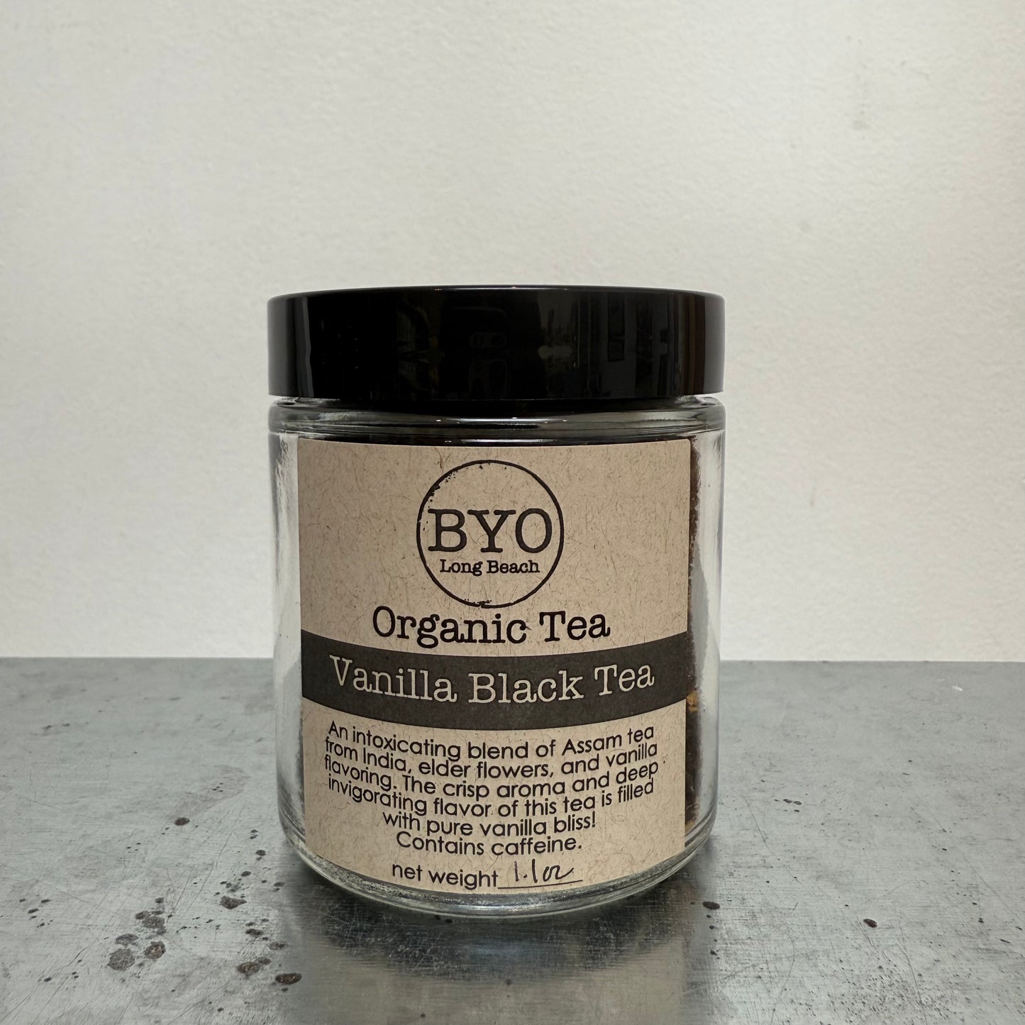 Jar of vanilla black tea with a black lid on a gray surface