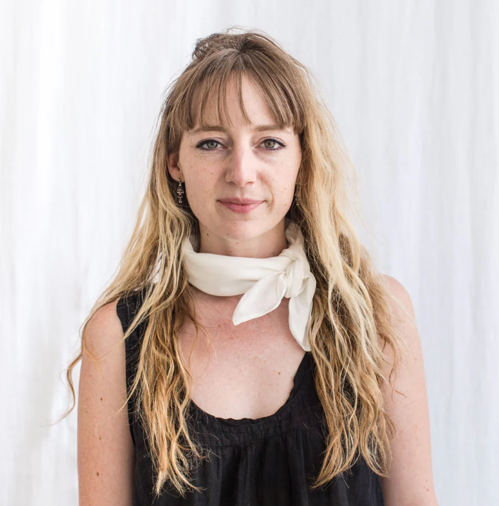 Woman wearing a white scarf against a plain background