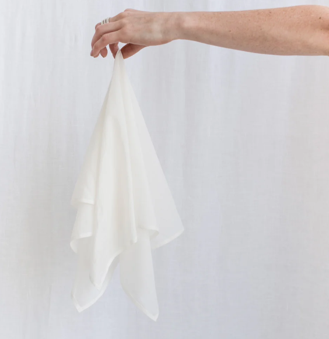 Person holding a white fabric against a plain background