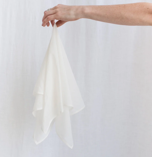 Person holding a white fabric against a plain background