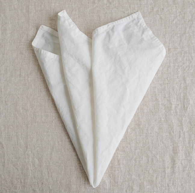 Folded white napkin on a textured beige surface