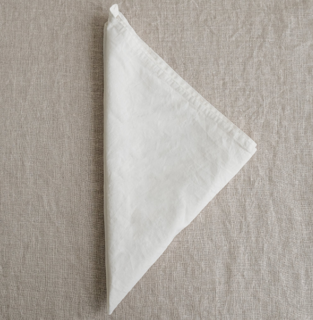 White folded napkin on a textured beige surface