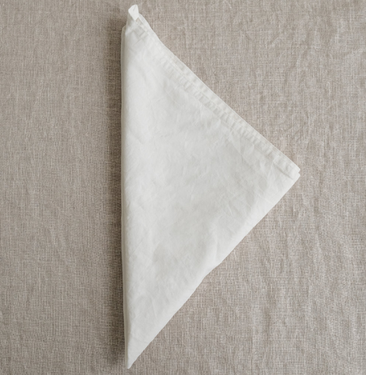 White folded napkin on a textured beige surface
