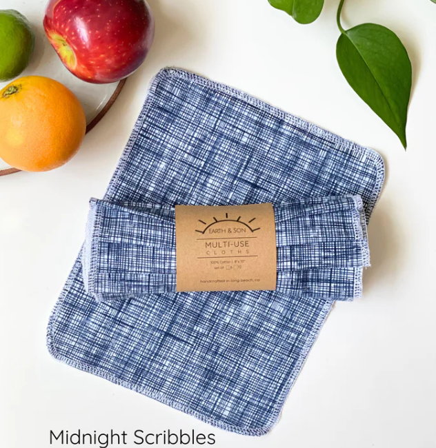 Blue plaid cloth with a cardboard label on a white surface with fruits and leaves.