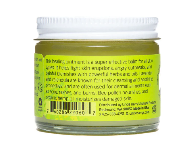 Jar of healing ointment with green label and white lid on a white background