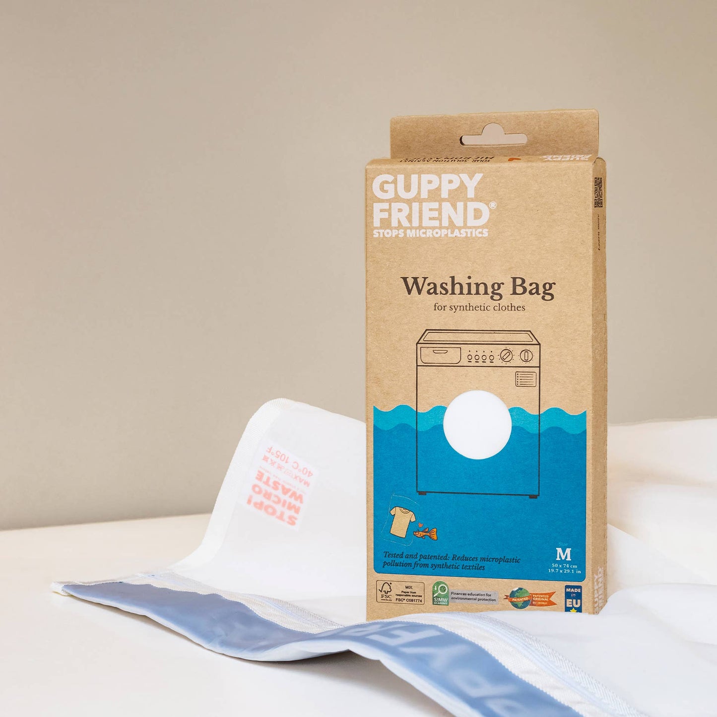 Guppy Friend washing bag packaging with a white washing bag on a beige background