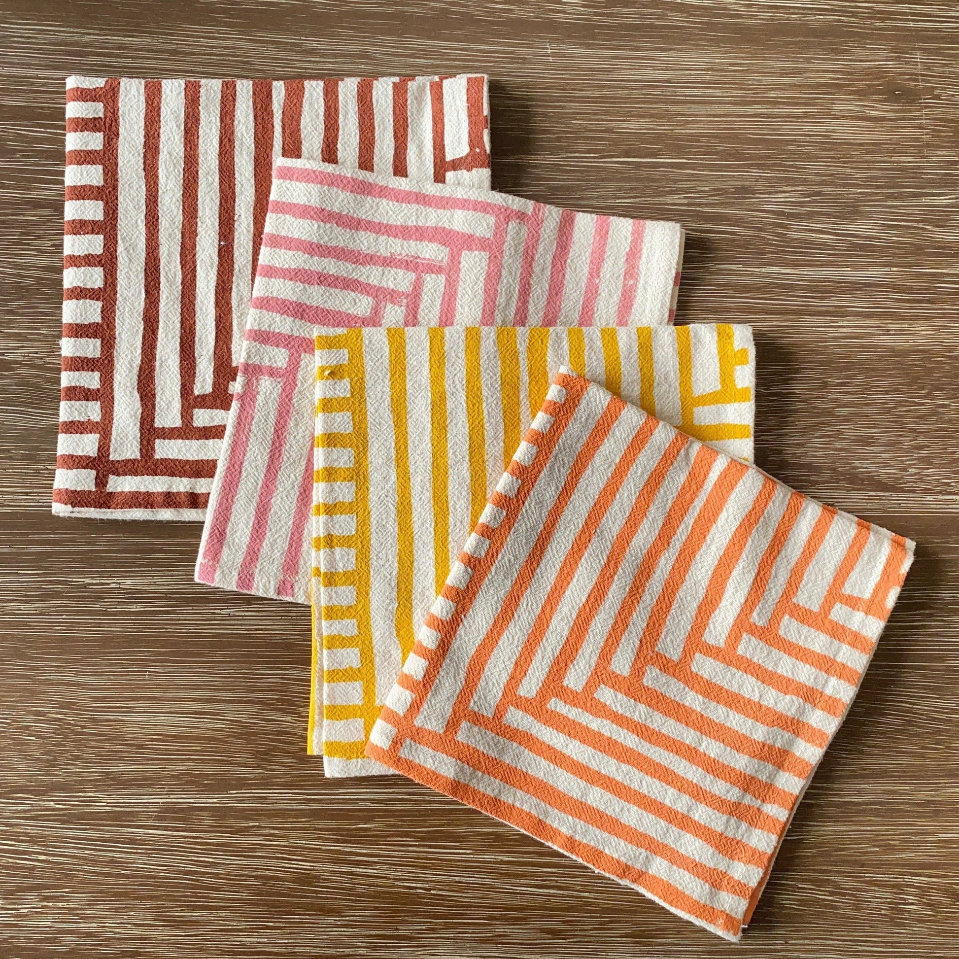 Set of four patterned napkins on a wooden surface