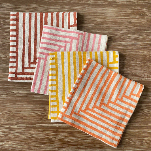 Set of four patterned napkins on a wooden surface