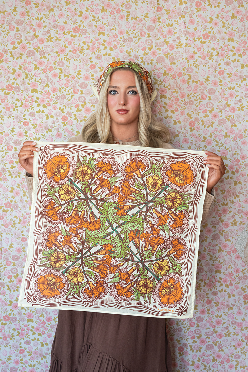 Woman holding a floral patterned fabric against a floral wallpaper background