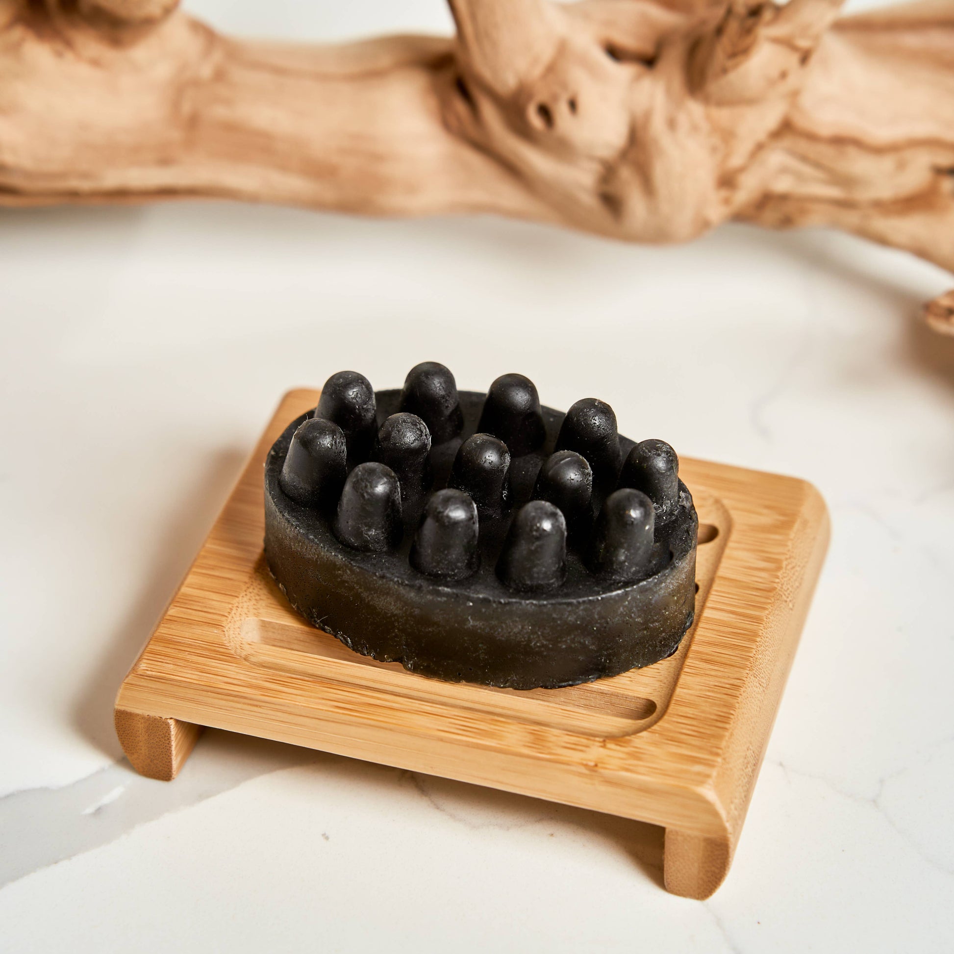 Black textured bar soap on a wooden stand with a natural wood background